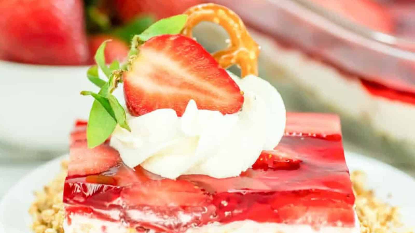 A jello dessert with berries and white layer on a crumb base. 