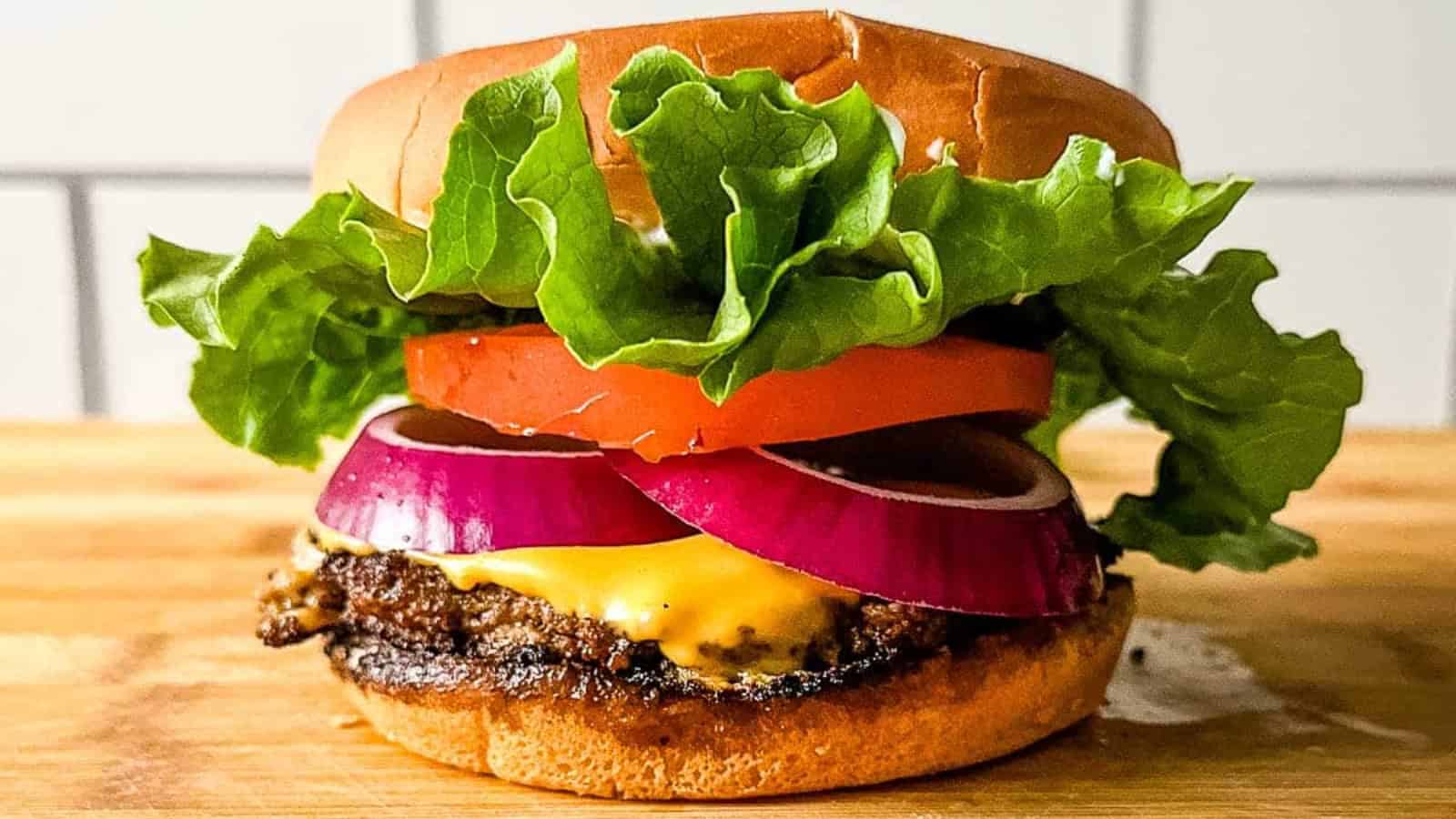 A turkey smash burger on a wooden cutting board in front of subway tile.