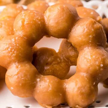 Close-up of glazed, round, bubble-shaped donuts arranged on a white decorative tray.