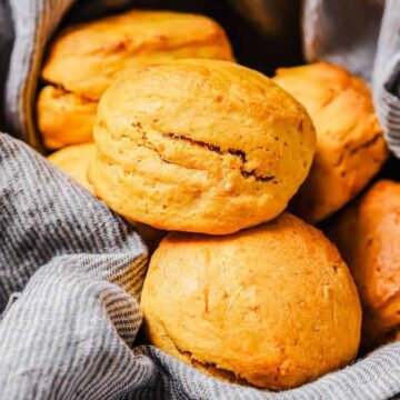 Golden brown biscuits in a bowl lined with a gray striped cloth.