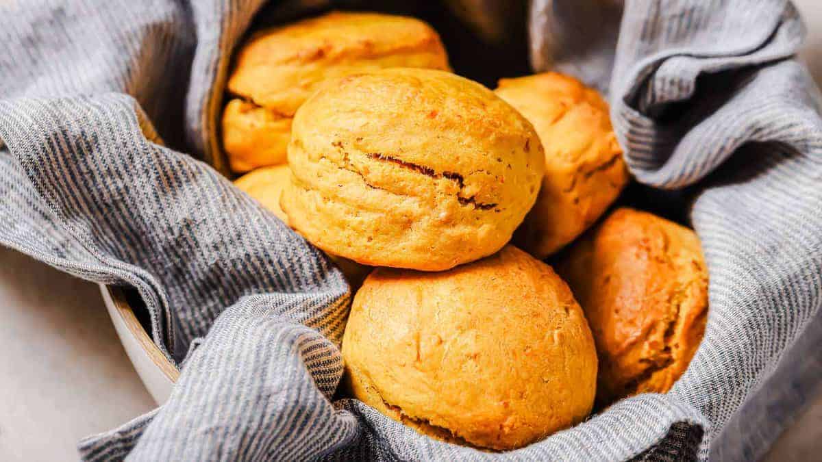 Golden brown biscuits in a bowl lined with a gray striped cloth.
