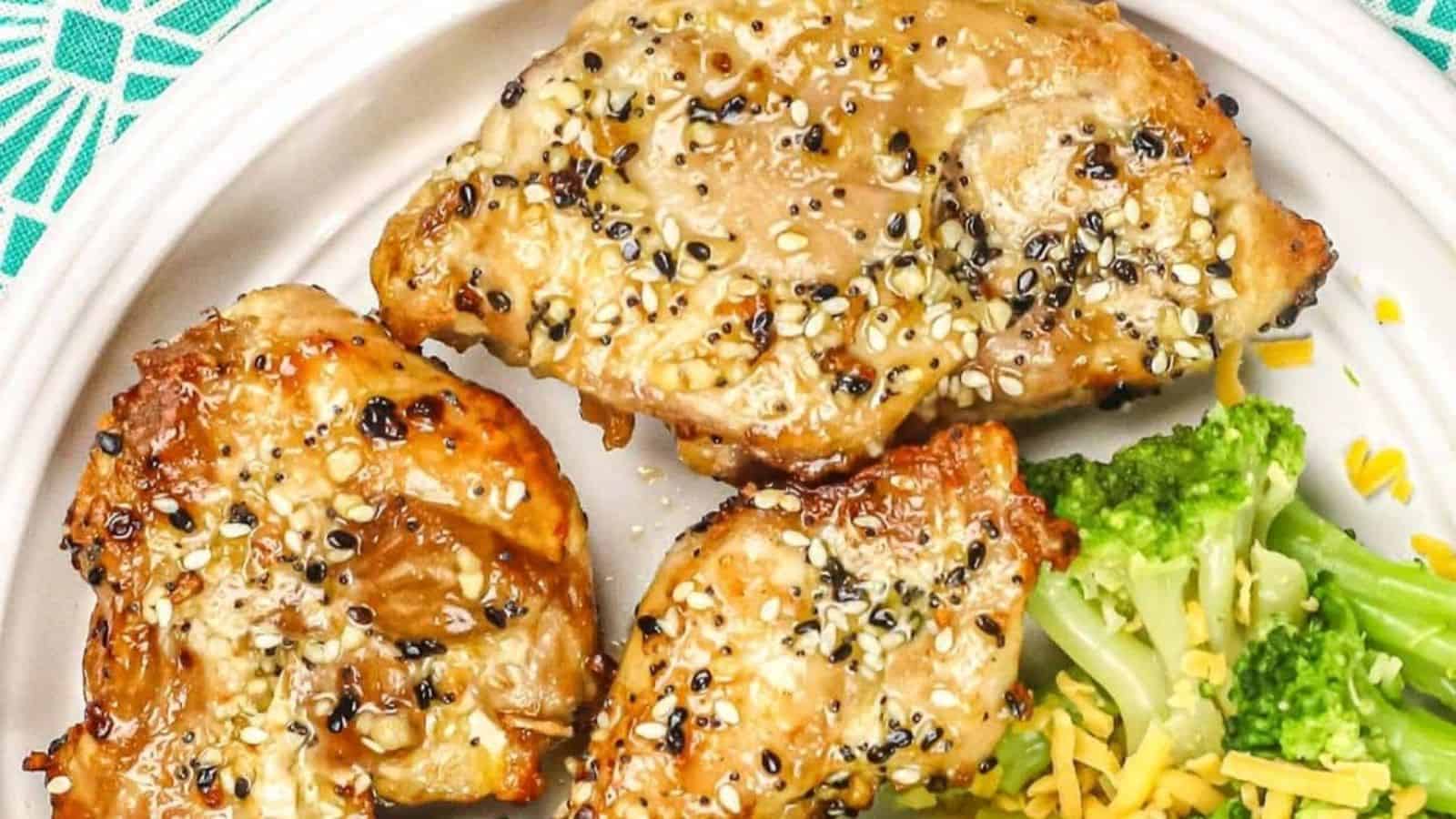 Three air-fried, sesame-crusted chicken thighs with broccoli on a white plate.
