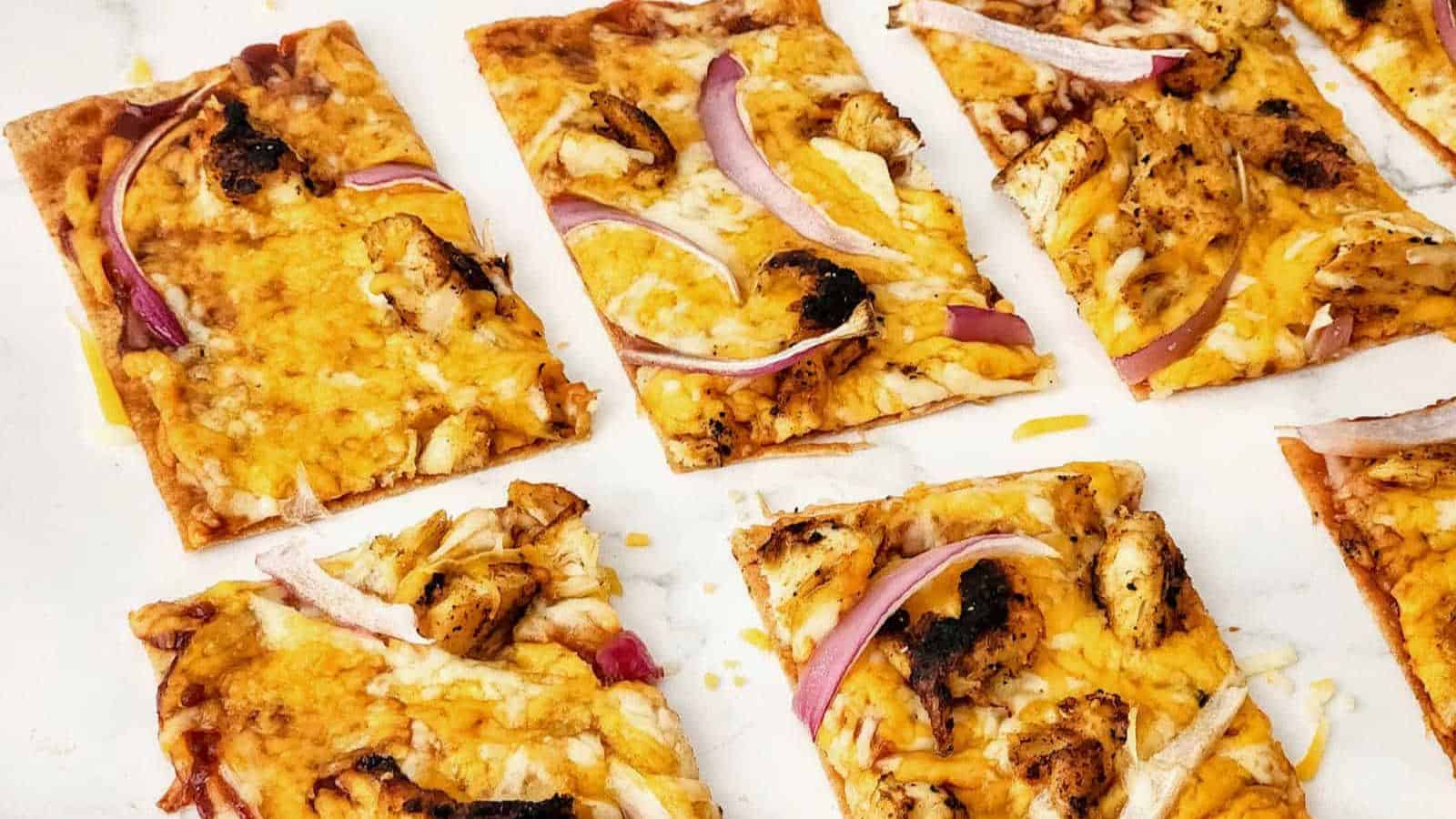 Grilled chicken flatbread pizzas on a marble countertop.