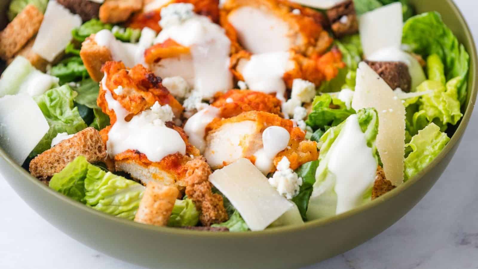 A bowl of Buffalo chicken caesar salad with dressing.