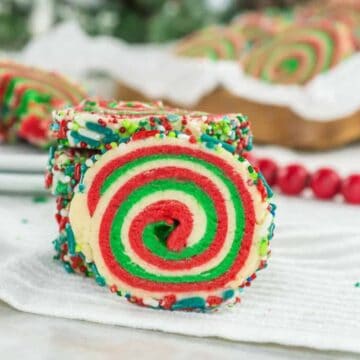 A festive spiral cookie with red, green, and white swirls, coated in colorful sprinkles.