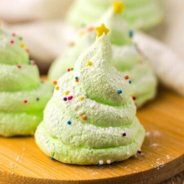 Light green meringue cookie shaped like a Christmas tree, topped with sprinkles and a yellow star.