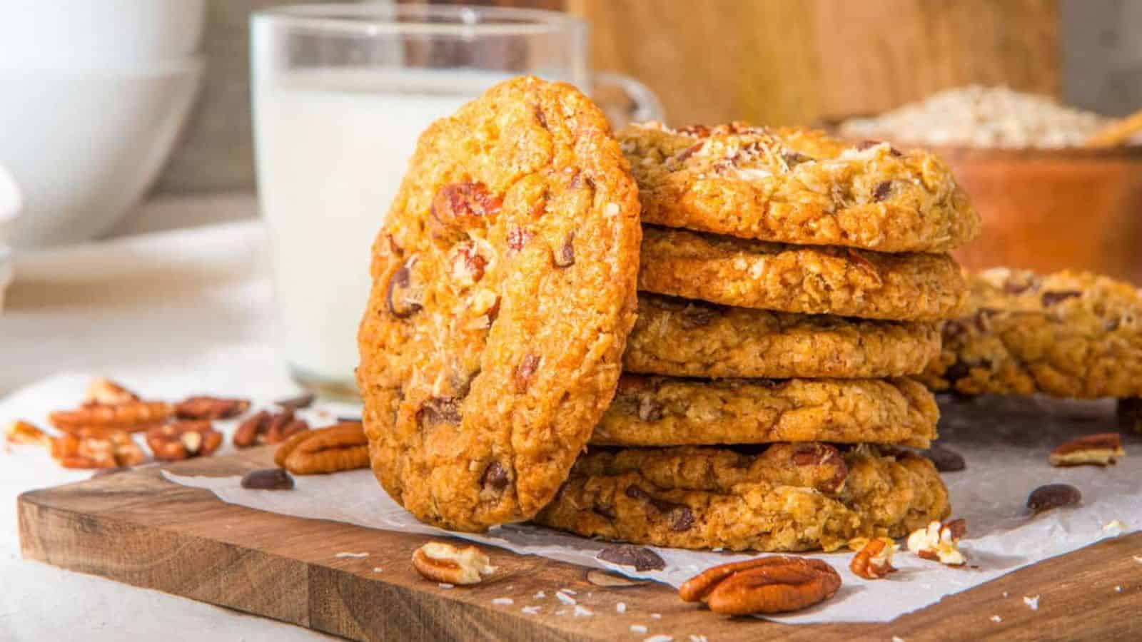 A close up image of a stack of cowboy cookies arranged on a serving platter with a glass of milk at the back.