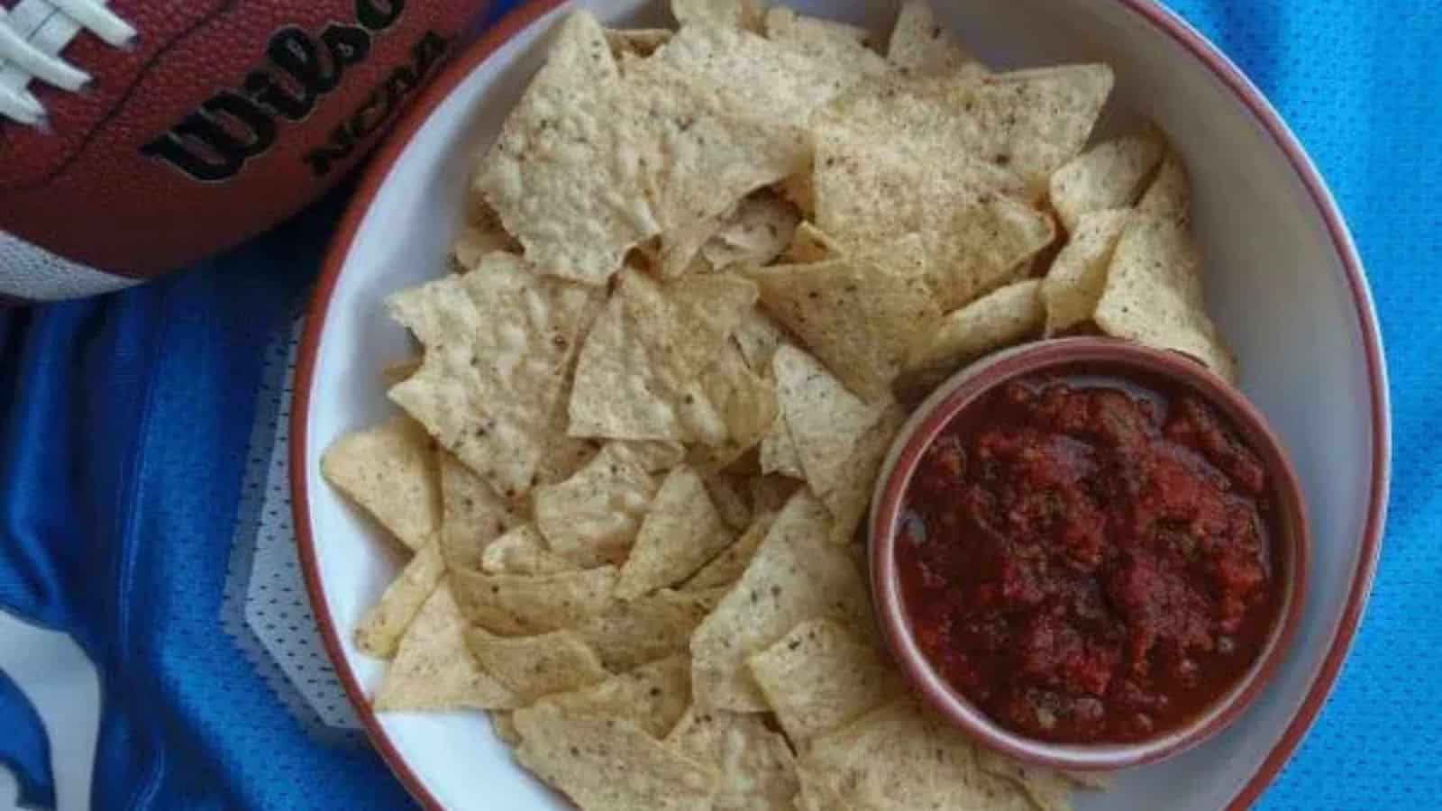 Bowl of chips with salsa and a football on a jersey.