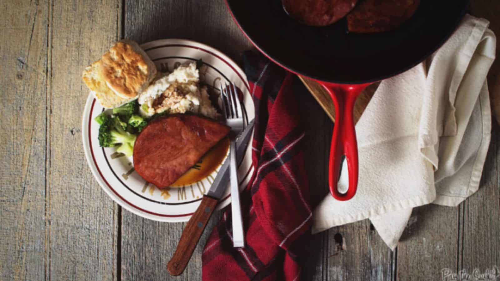 Ham steak glazed with brown sugar caramelizing on edges.