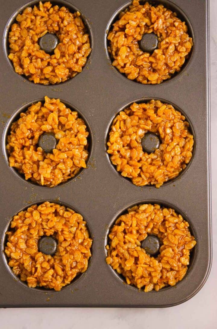 Six Pumpkin Rice Krispies Donuts shaped like classic donuts in a nonstick donut baking pan.