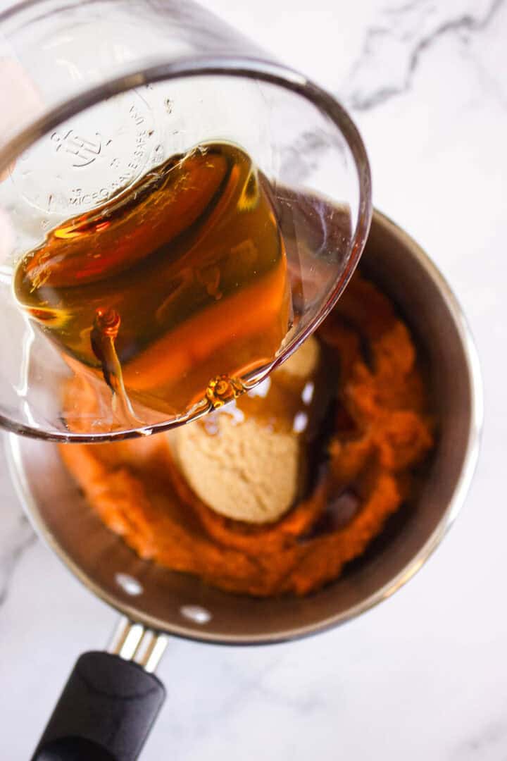 A glass measuring cup pours liquid into a saucepan with pumpkin puree and brown sugar&mdash;the perfect start for making Pumpkin Br&ucirc;l&eacute;e Tarts.