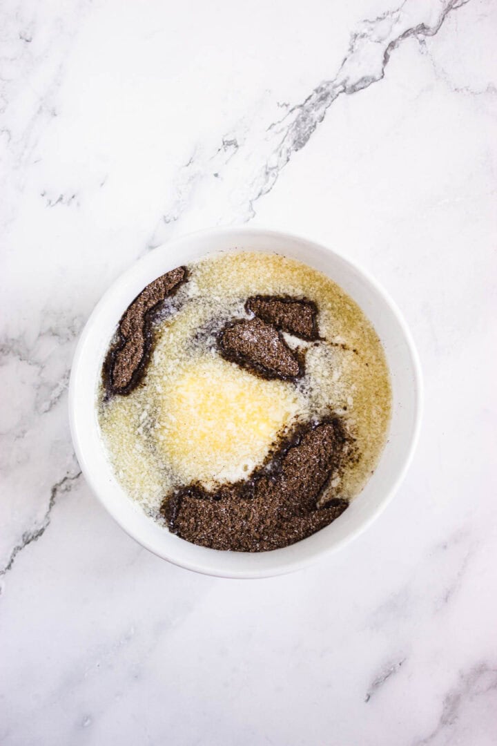 A white bowl with melted butter and brown sugar on a marble surface, perfect for preparing Pumpkin Br&ucirc;l&eacute;e Tarts.