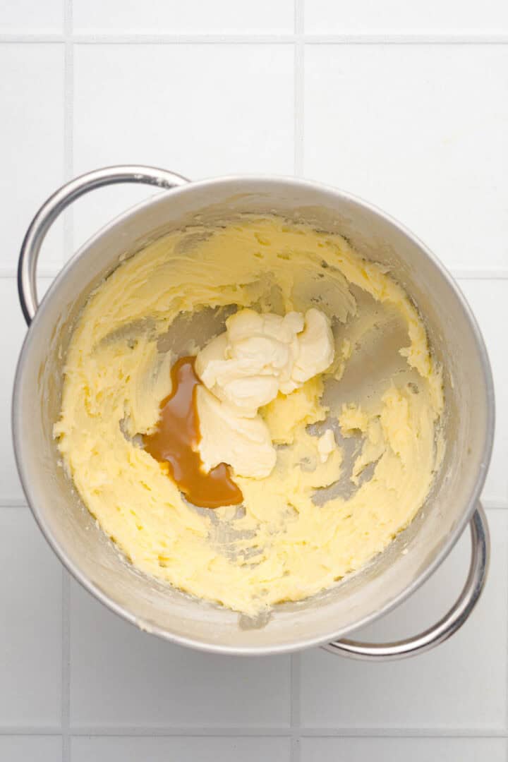 A metal mixing bowl with creamed butter, cream, and vanilla extract on a white tiled surface&mdash;perfect for starting a batch of Salted Caramel Pumpkin Muffins.