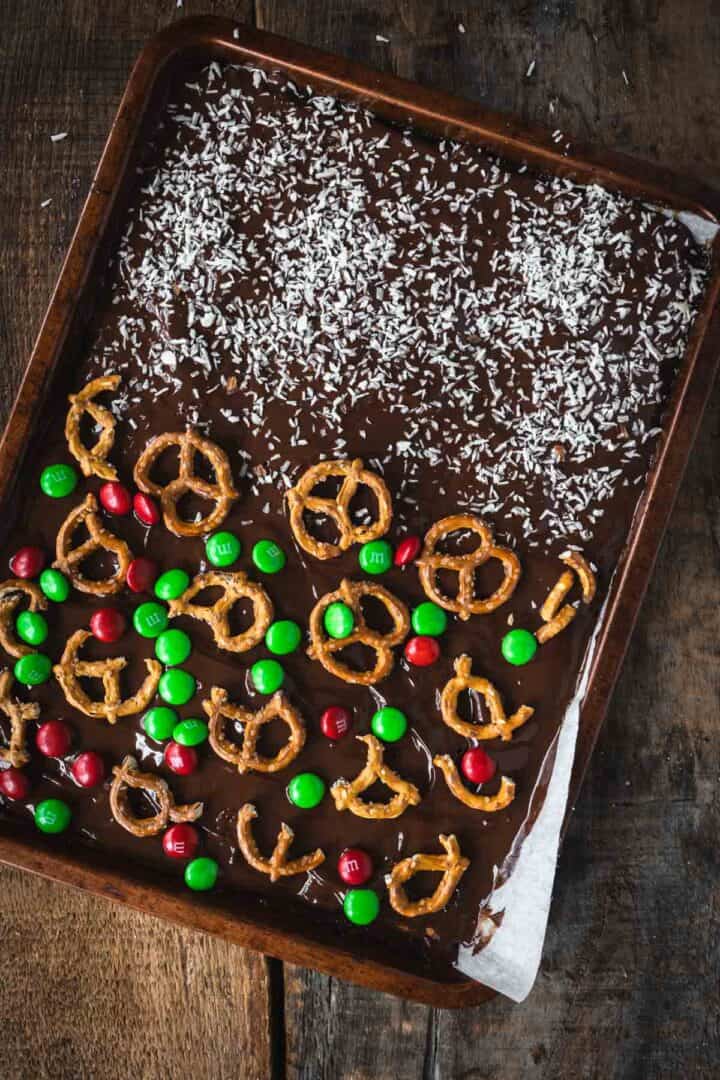 A tray of Christmas Toffee Bark topped with pretzels, red and green M&Ms, and shredded coconut.