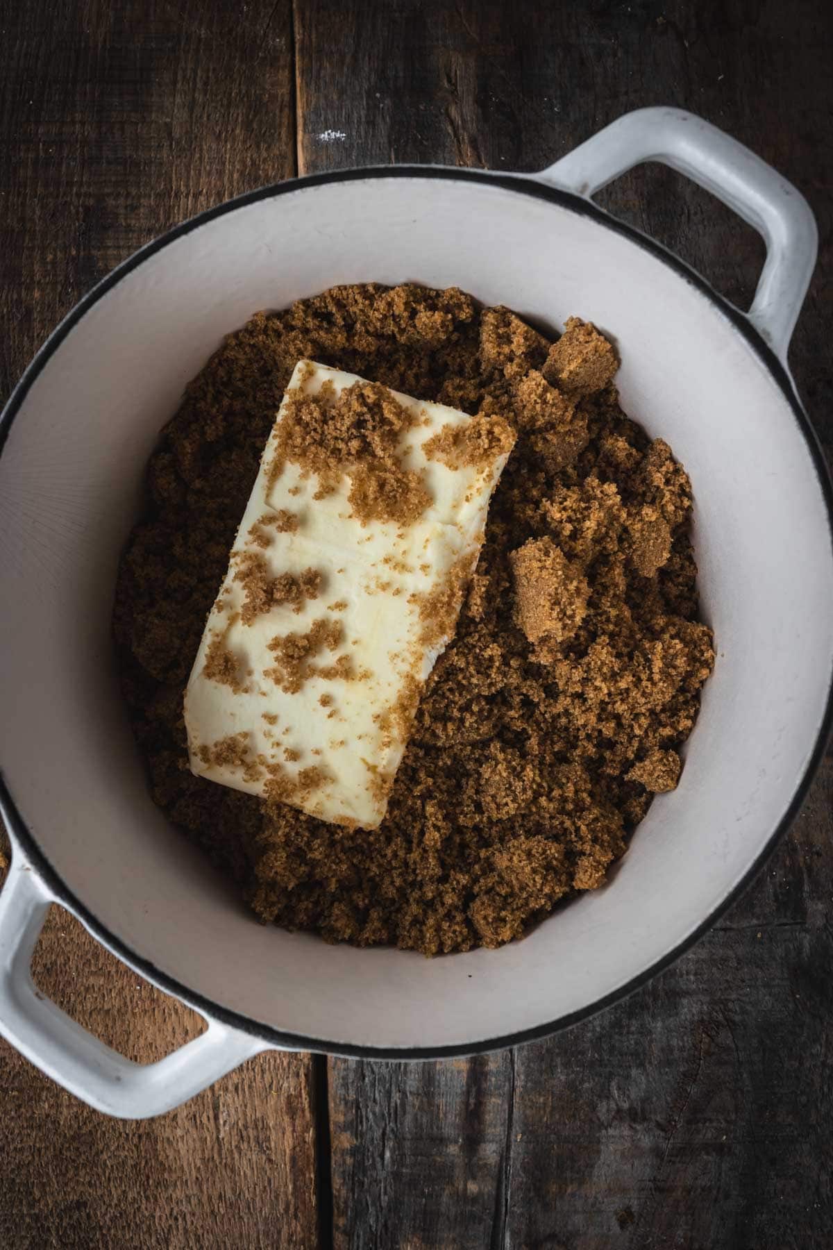 A white pot with a stick of butter and brown sugar on a wooden surface&mdash;perfect for starting your homemade Christmas Toffee Bark.