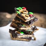 Stack of Christmas Toffee Bark with pretzels, colorful candies, and graham crackers on parchment paper.