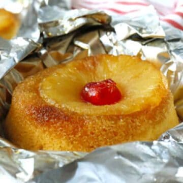 A pineapple upside-down cake with a cherry on top, baked in foil and ready to serve.