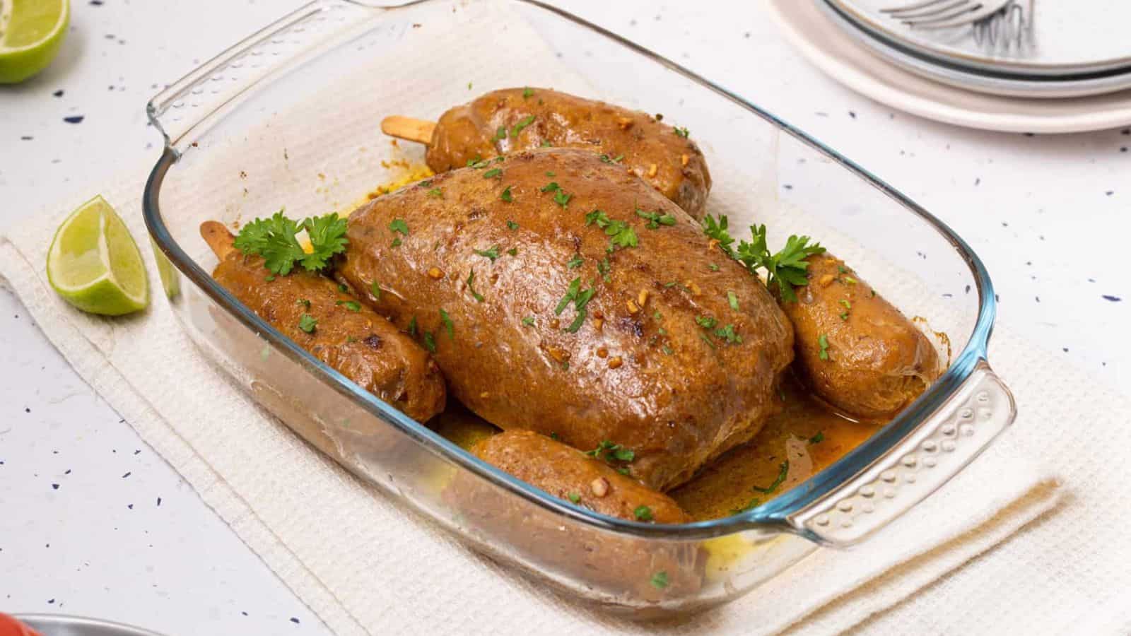 Vegan Turkey Roast in a glass baking dish on a countertop, garnished with herbs.