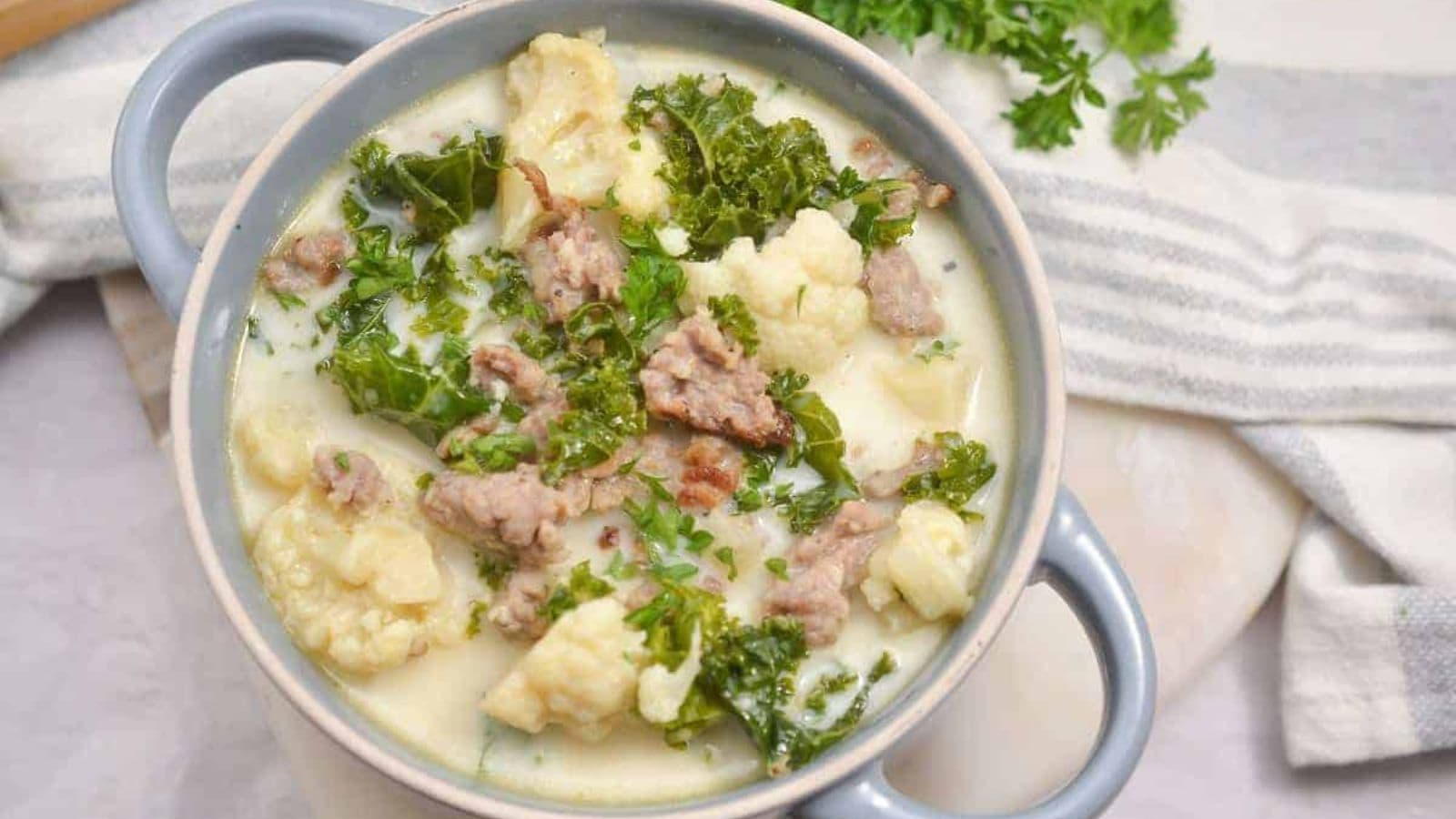 A bowl of soup with meat and kale.