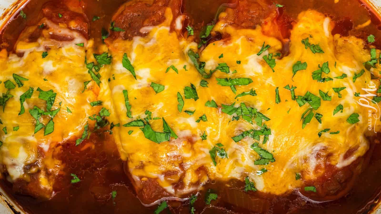 Three stuffed peppers covered in melted cheese and garnished with chopped parsley in a tomato sauce&mdash;perfect for anyone looking for delicious Budget Recipes.