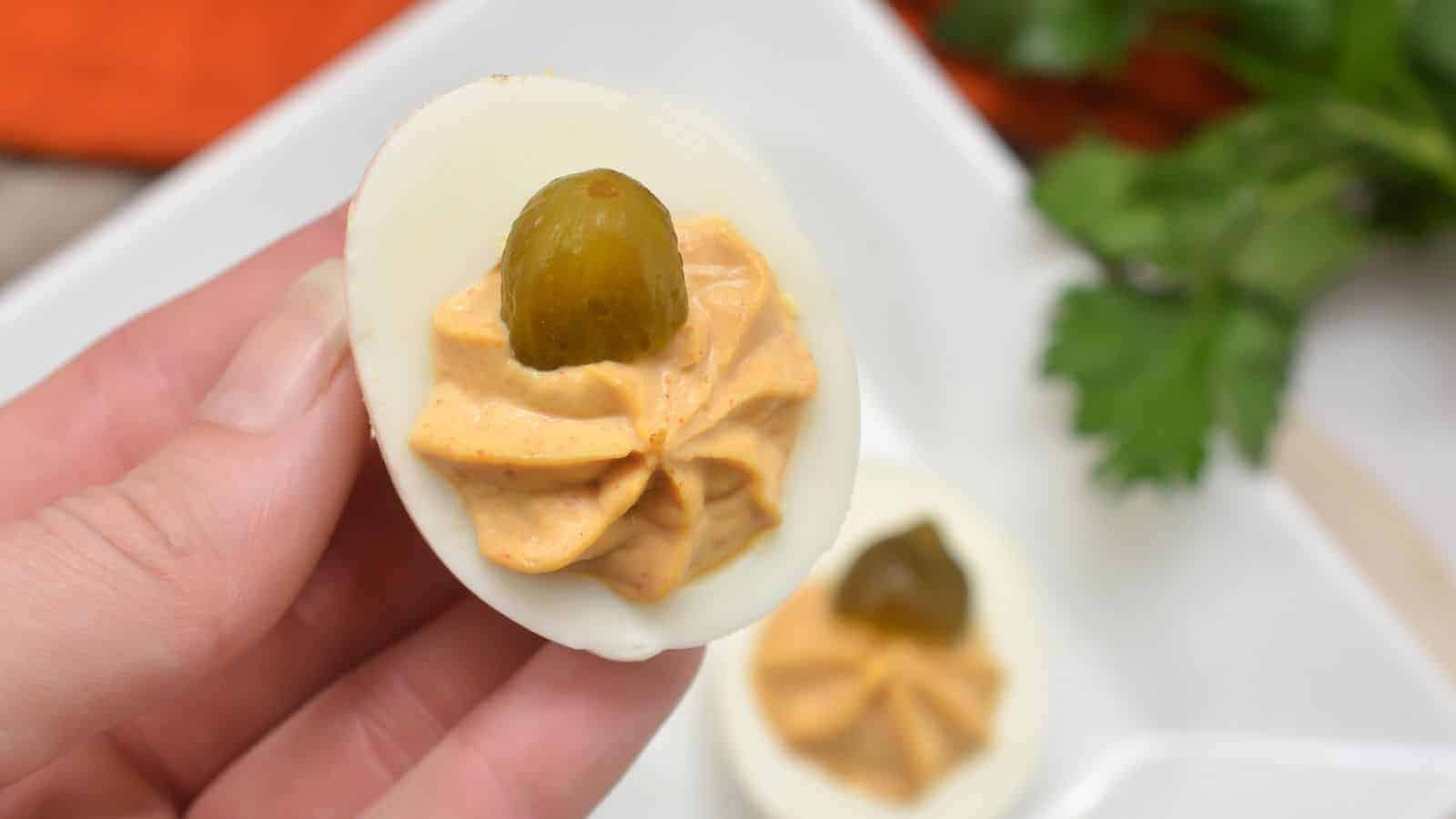 Pumpkin deviled eggs on a white plate.