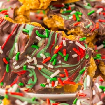 Chocolate bark with red, green, and white sprinkles on a plate, festive holiday background.