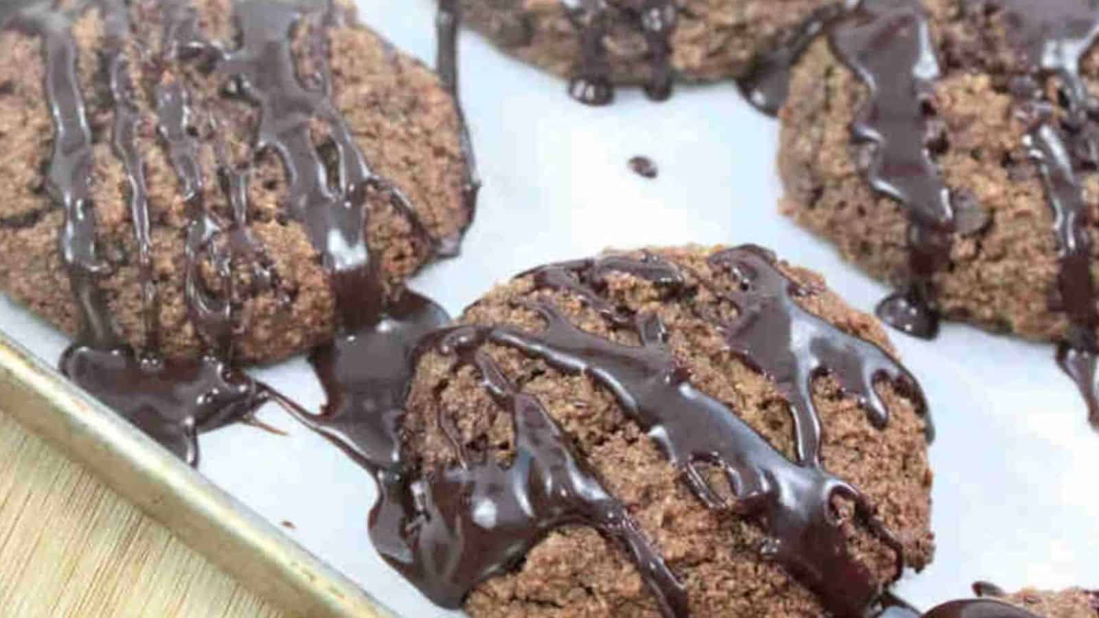 Chocolate cookies on a baking tray, drizzled generously with melted chocolate.