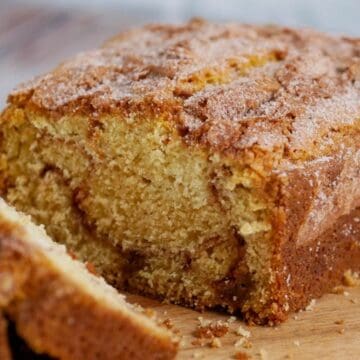 A sliced loaf of cinnamon swirl bread sits on a wooden cutting board.