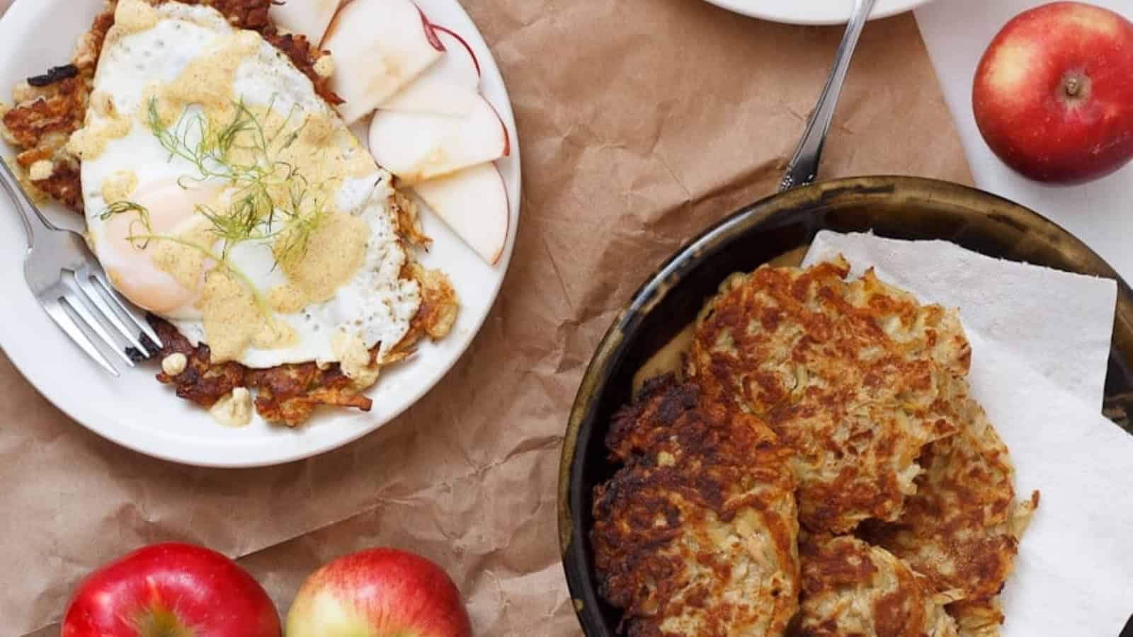 Apple potato latkes with curried yogurt sauce and applesauce on a white plate.