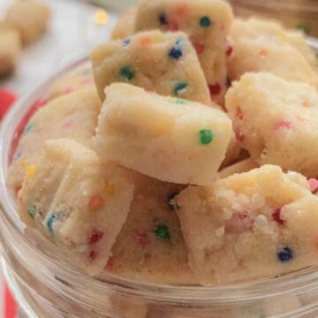 Bite-sized pieces of funfetti shortbread cookie dough in a glass jar.