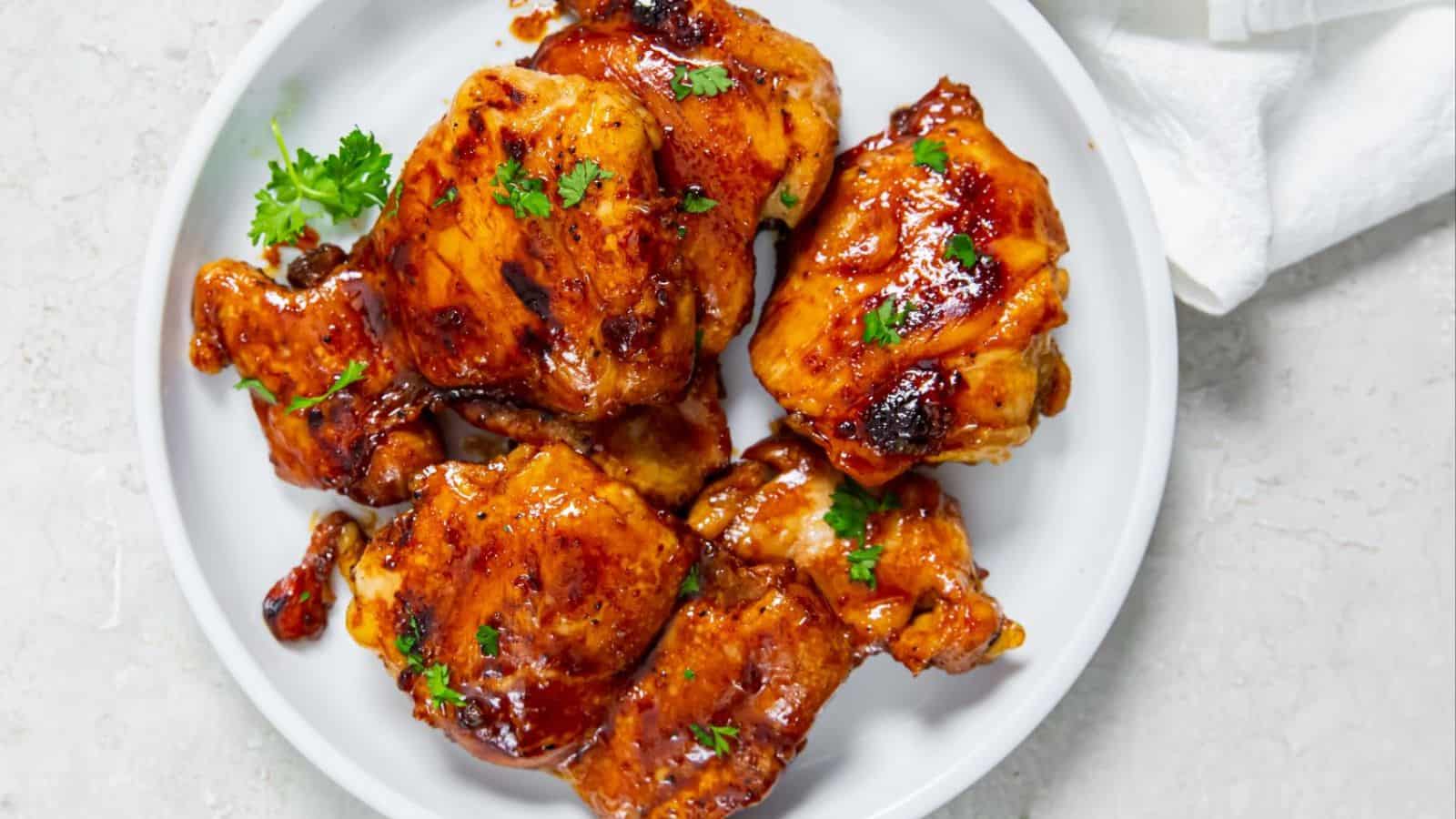 Honey Lemon Pepper Thighs with parsley on a white plate.