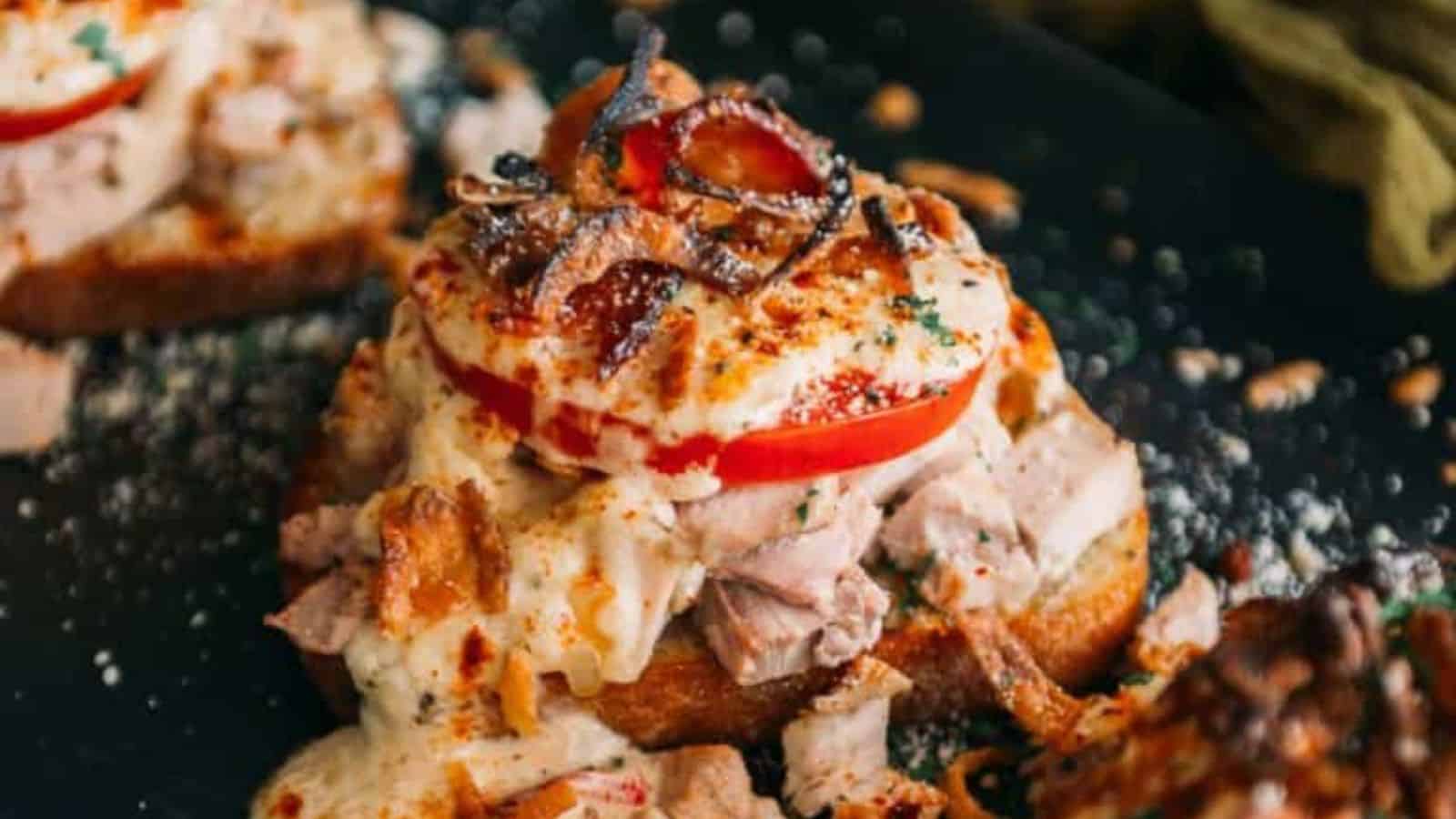 Hot Brown sandwich topped with turkey, sauce, and bacon.