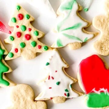 Assorted decorated Christmas cookies shaped like trees, mittens, and gingerbread people on a white background.