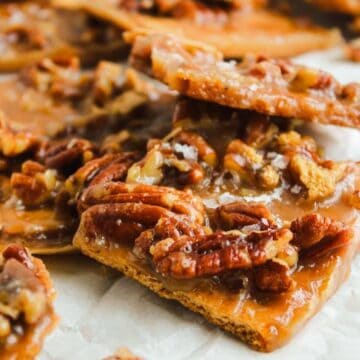 Close-up of pecan pie bark with caramelized pecans on top of graham crackers, arranged on parchment paper.
