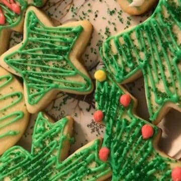 Christmas cookies decorated with green icing and sprinkles on a festive plate.