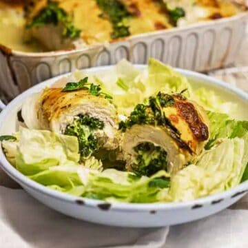 Rolled chicken breast stuffed with spinach and cheese, served on lettuce in a white dish.