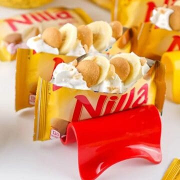 Nilla wafer packets filled with whipped cream and banana slices, displayed on colorful holders.
