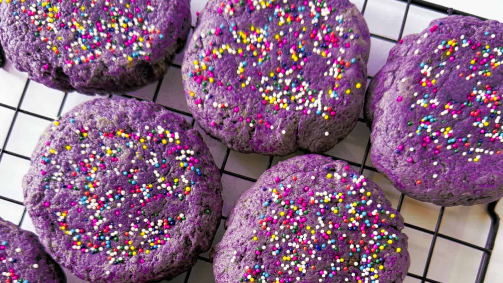 Chewy and vibrant ube cookies on a black cooling rack.