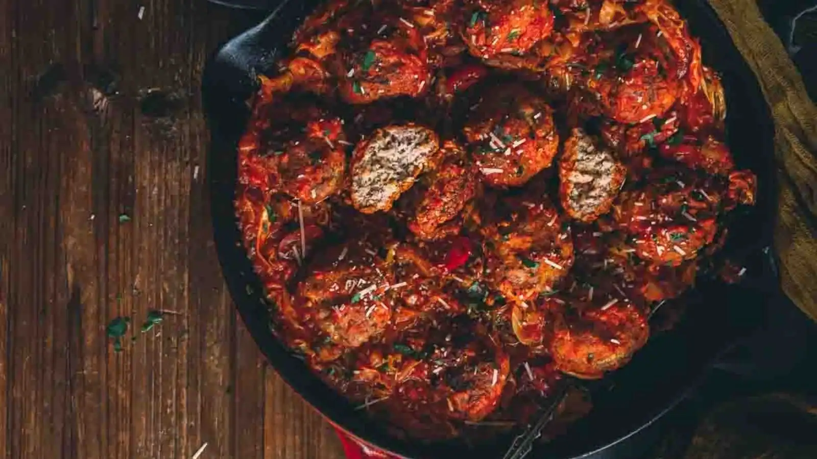 Small veal meatballs browned and simmered in sauce arranged in a skillet.