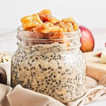 A jar of chia seed pudding topped with caramelized apple pieces, with apples in the background.