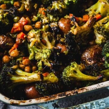 A casserole dish filled with roasted broccoli, potatoes, chickpeas, and diced vegetables.