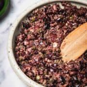 A bowl of Easy Olive Tapenade being mixed with a wooden spoon.