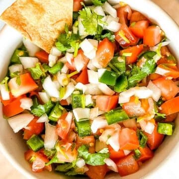 A bowl of salsa with a chip in it.