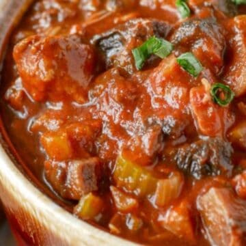 A bowl of chunky beef stew with tomato sauce, vegetables, and fresh herbs on top—a comforting nod to forgotten recipes.