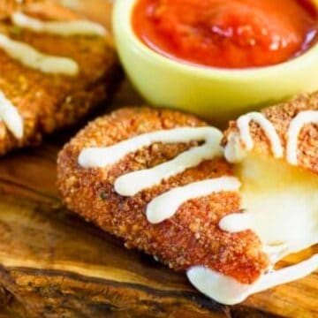 Breaded, fried mozzarella sticks with melted cheese inside, drizzled with sauce, and served with marinara dip.