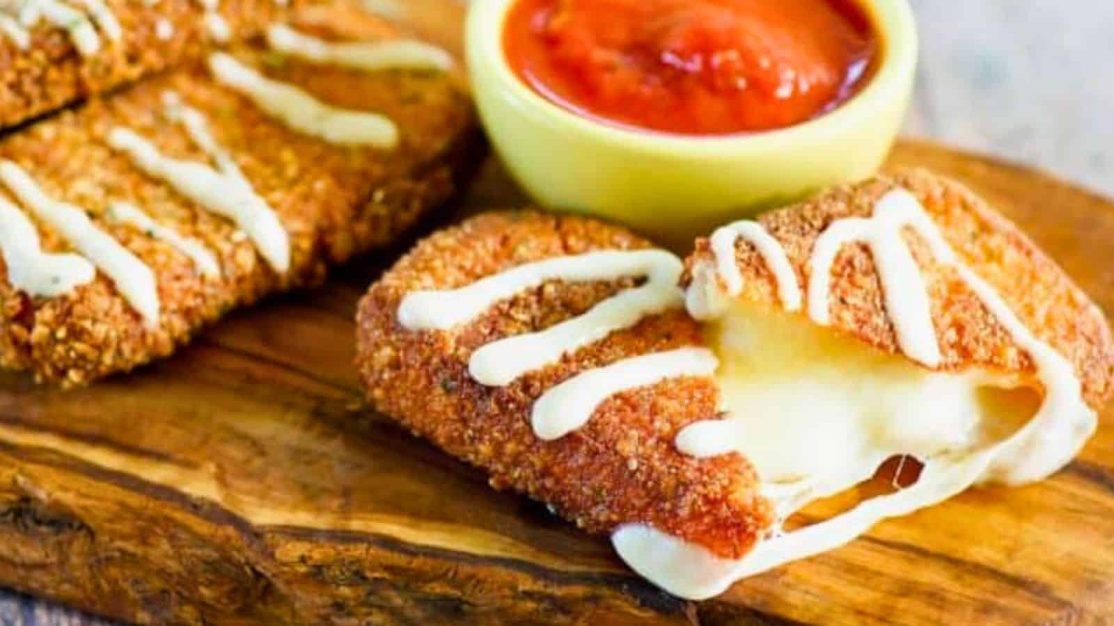Breaded, fried mozzarella sticks with melted cheese inside, drizzled with sauce, and served with marinara dip.