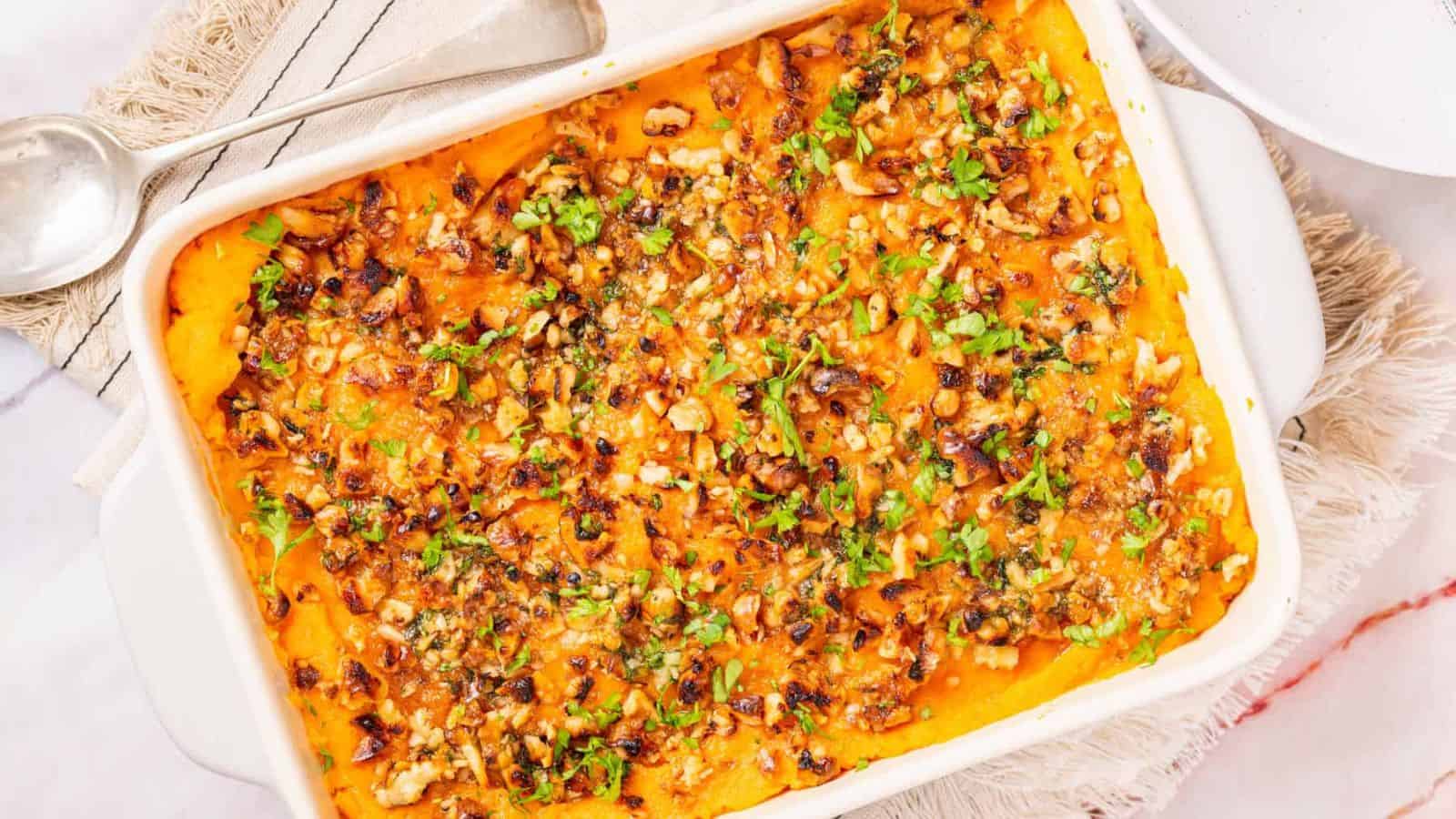 An angled shot of savory sweet potato casserole served in a baking dish.