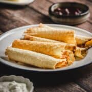 A plate of traditional Russian rolled wafers sits on a wooden table, with small bowls of jam and cream nearby.