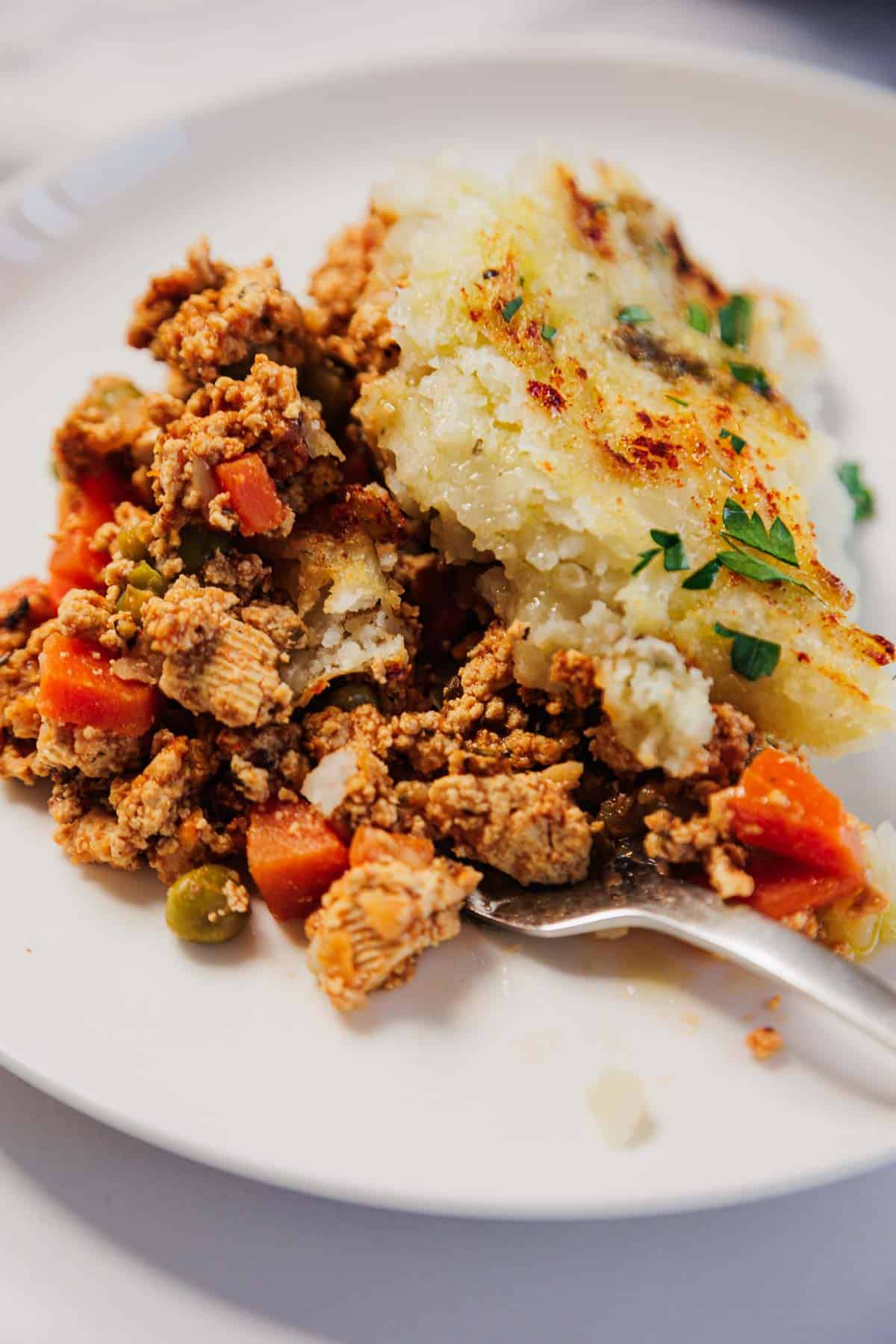 A plate of Vegetarian Shepherd's Pie with hearty vegetables and a golden mashed potato topping, served with a fork.
