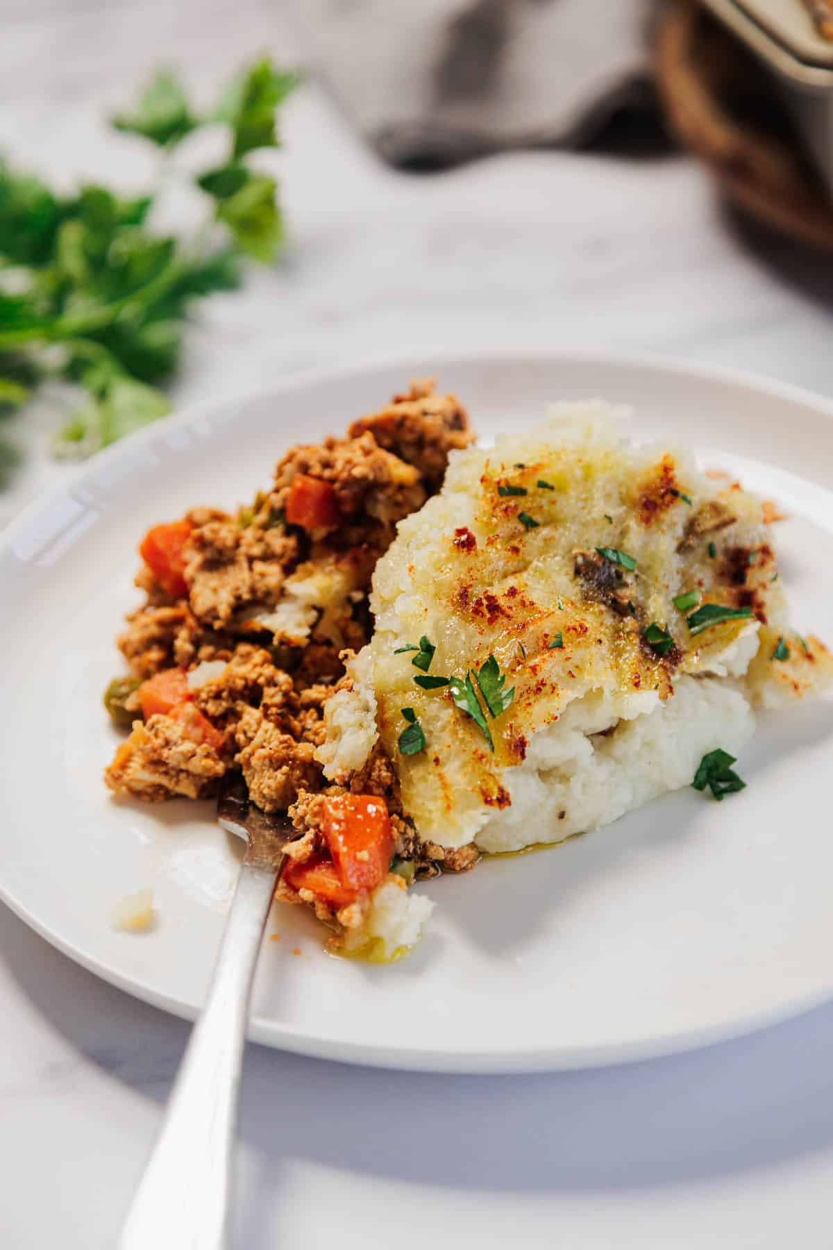 A plate of Vegetarian Shepherd's Pie with hearty vegetables and creamy mashed potatoes, garnished with fresh parsley.